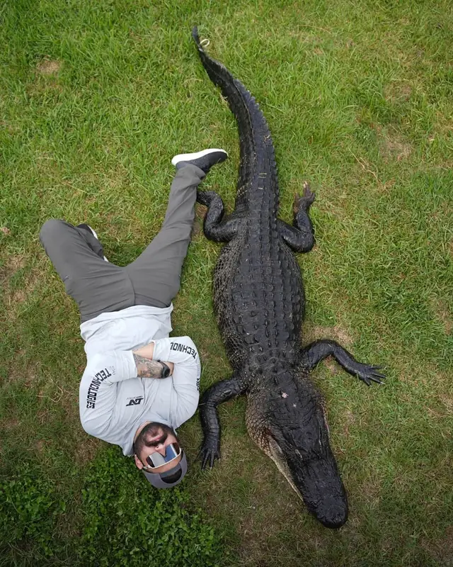 Hunter beside an alligator showing its length after a guided hunt