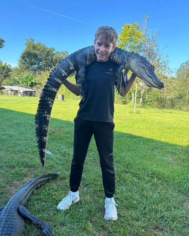 Teenage hunter carrying an alligator across his shoulders