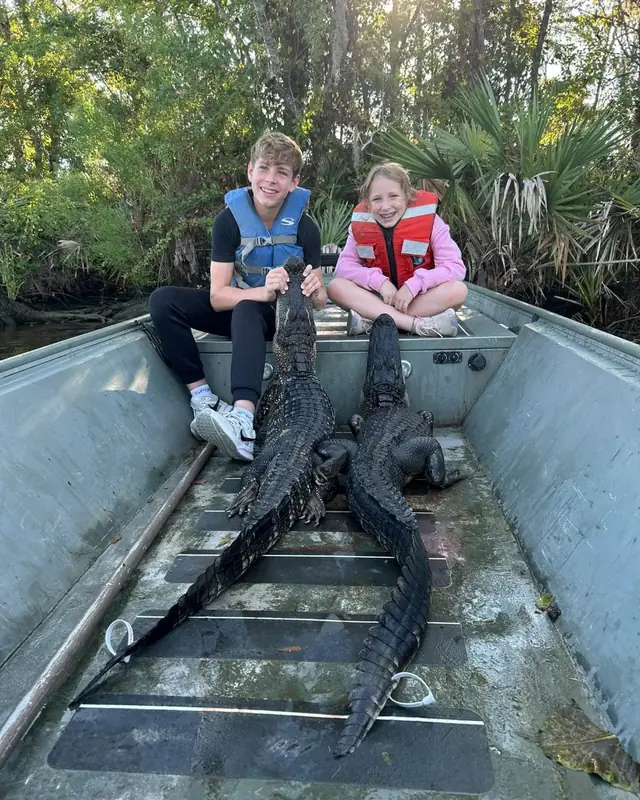 Young hunters in the boat with two alligators from a family hunt
