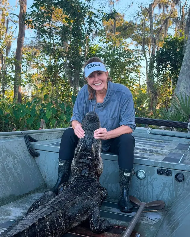 Woman hunter with a trophy alligator in the boat after a guided Louisiana hunt