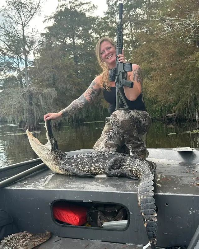Hunter with a rifle and an alligator on the boat deck