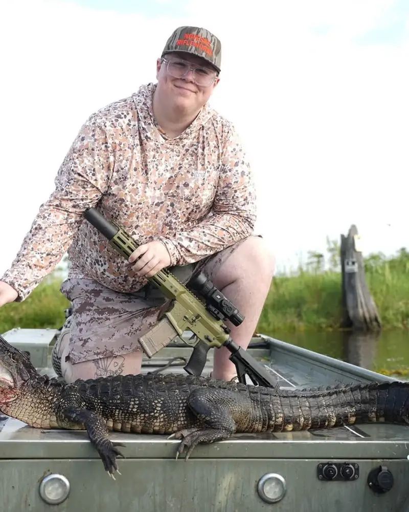 Camouflaged hunter in a jon boat working the marsh on a guided Louisiana alligator hunt