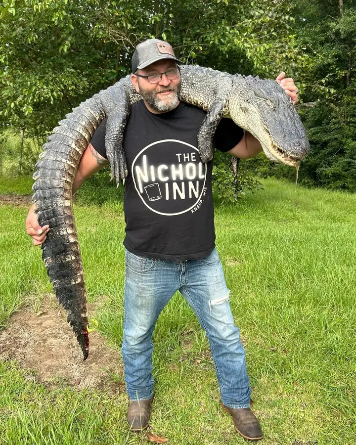 Hunter carrying an alligator across his shoulders after a Louisiana gator hunt