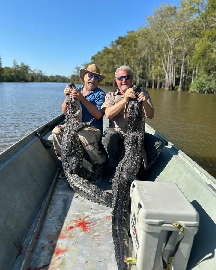 Two hunters in a boat with the day's alligator harvest