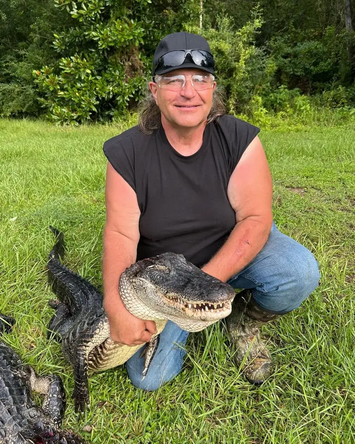 Hunter holding an alligator by the head after a guided hunt in Louisiana